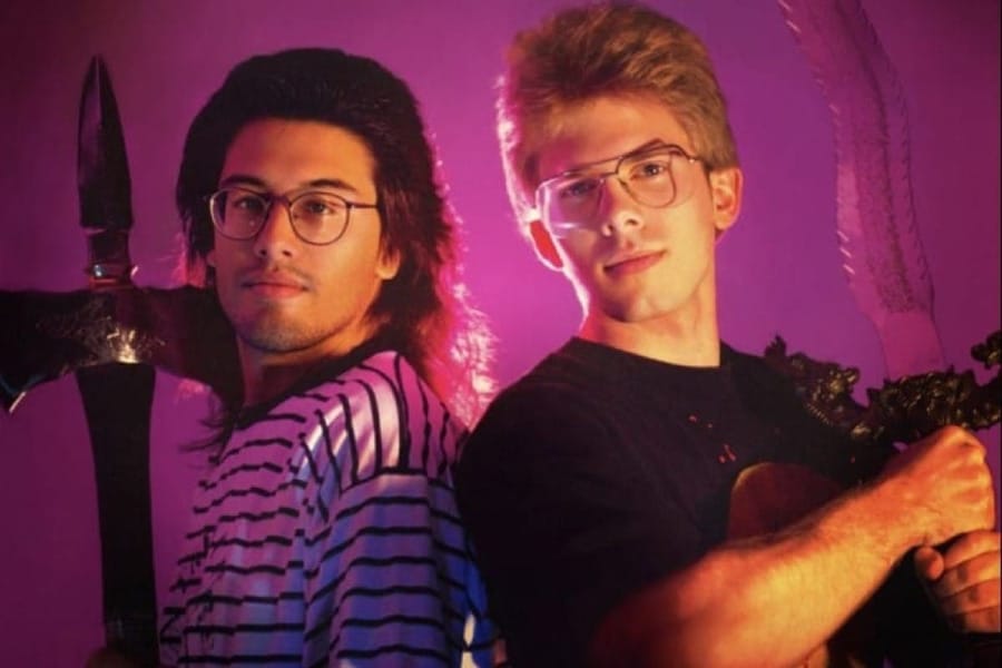 John Romero and John Carmack in an old photo holding medieval weapons.