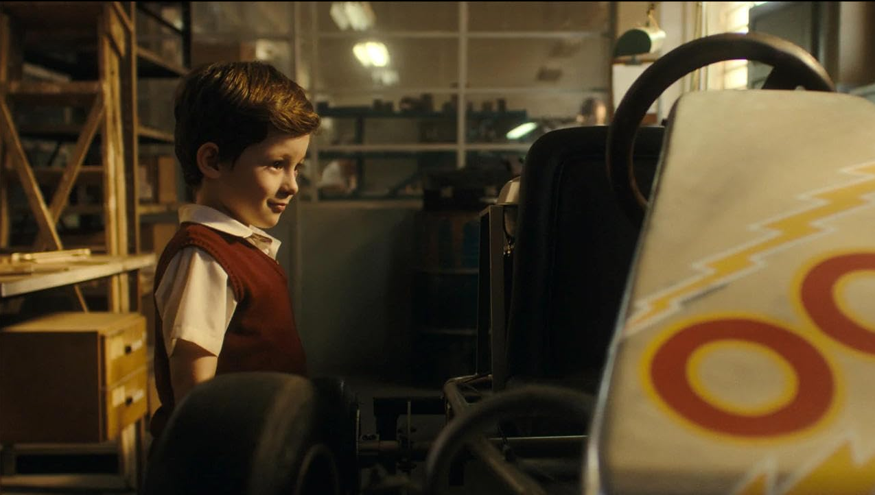  A little Ayrton Senna stands in a warm, dusty garage looking at a racing kart with a smile.